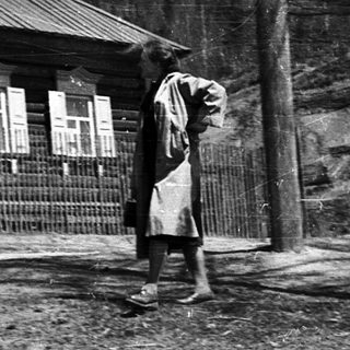 Rural scene with two people near wooden house.