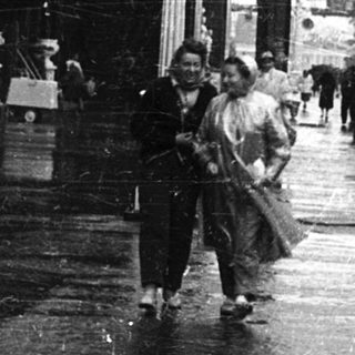 Vintage train station platform with wet pavement and pedestrians.