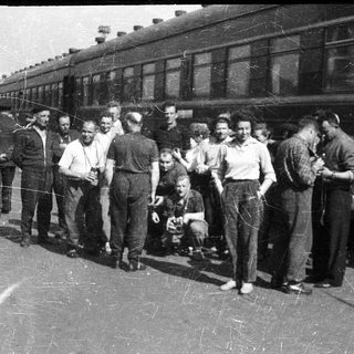 Group of people posing near a vintage train.