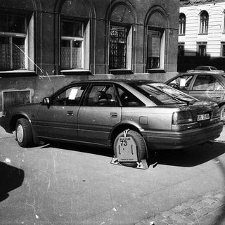 Vintage sedan parked with parking block on wheel.