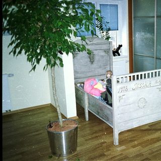 Vintage wooden crib with child inside, labeled 1908.