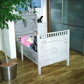 Vintage wooden crib with child inside, labeled 1908.