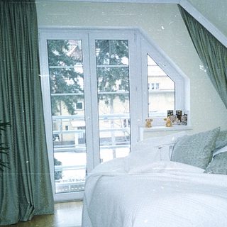 Cozy bedroom with large bed, sliding glass doors, and greenery.