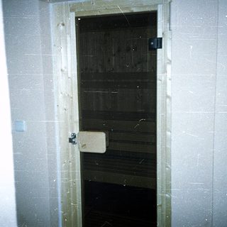 Boarded-up interior door with tiled walls.
