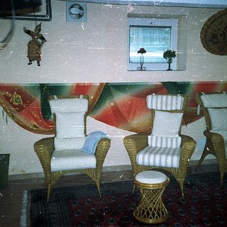 Vintage-style seating area with wicker chairs, striped cushions, and tropical decor.