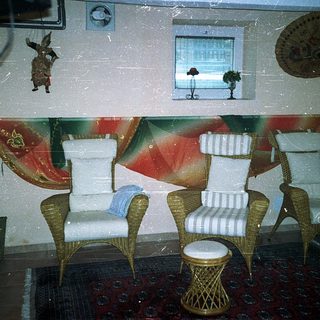 Vintage-style seating area with wicker chairs, striped cushions, and tropical decor.