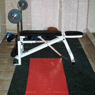 Home gym with bench press station and weights.