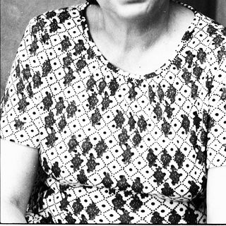Black-and-white portrait of an older woman in patterned blouse.