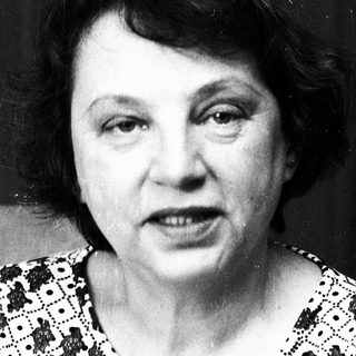 Black-and-white portrait of an older woman in patterned blouse.