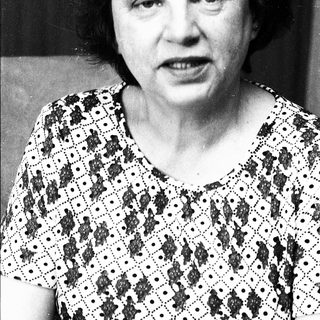 Black-and-white portrait of an older woman in patterned blouse.