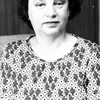 Black-and-white portrait of an older woman in patterned blouse.