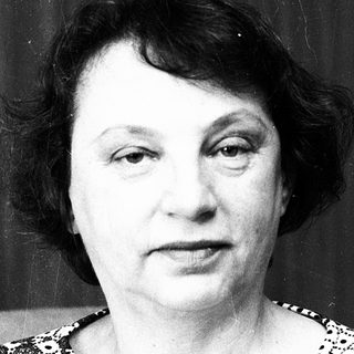 Black-and-white portrait of an older woman in patterned blouse.