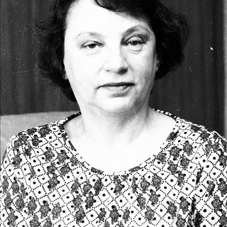 Black-and-white portrait of an older woman in patterned blouse.
