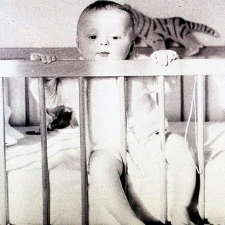 Baby peeking over crib railing.