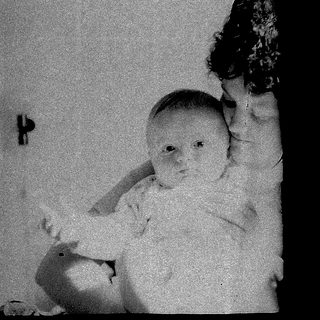 Baby standing indoors with adult holding.
