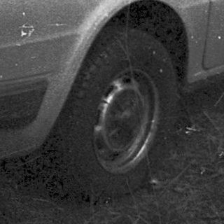 Vintage hatchback car parked on grassy area.