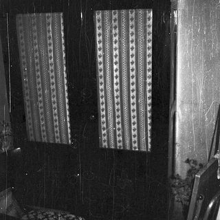 Dark room with patterned curtains, rain on window.