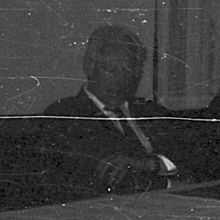 Dark room with blurred figures seated at table.