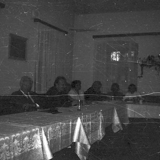Dark room with blurred figures seated at table.