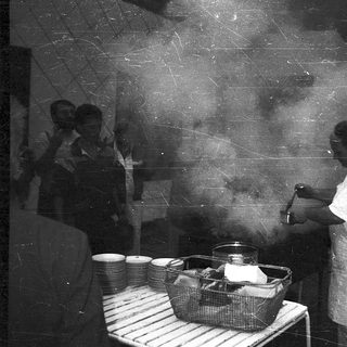 Cook preparing food in a steam-filled kitchen.