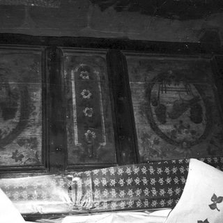 Vintage wooden cabinet with faded floral and geometric panel designs.