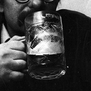 Man drinking beer indoors with glasses.