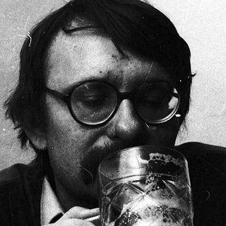 Man drinking beer indoors with glasses.