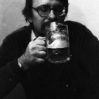 Man drinking beer indoors with glasses.