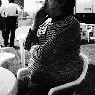 Man smoking outdoors at an outdoor café.