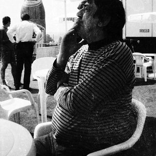 Man smoking outdoors at an outdoor café.