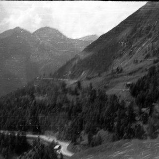 Mountainous landscape with winding road and dense forest.