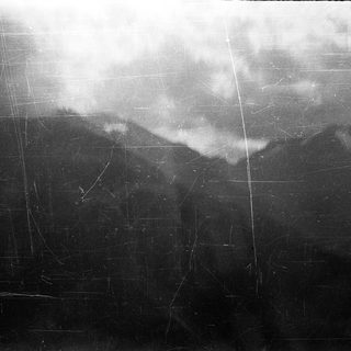 Blurred aerial view of cloud-covered mountainous terrain.