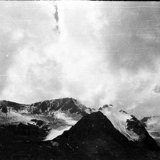 Volcanic landscape with active crater and cloudy skies.