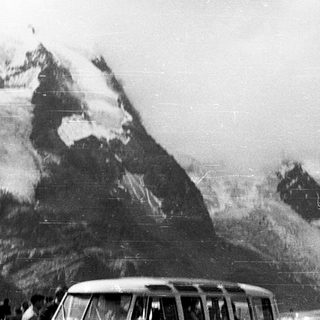 Snow-covered mountains with a vintage car below.