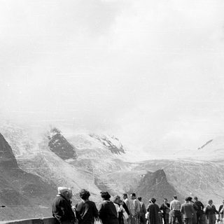 Group of people viewing snow-covered mountain peak.