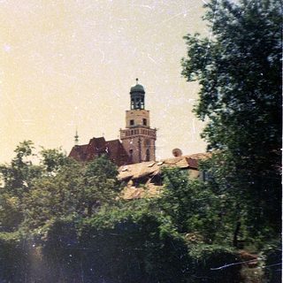 Historic town with castle tower and red-roofed buildings.