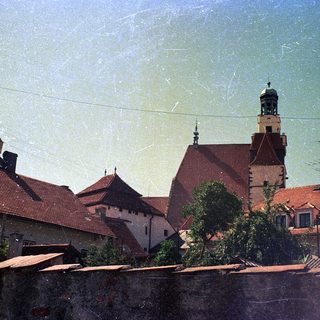 Historic European town with red-tiled roofs and church tower.