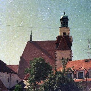 Historic European town with red-tiled roofs and church tower.