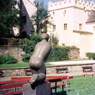 Medieval castle with courtyard, benches, and sculpture.