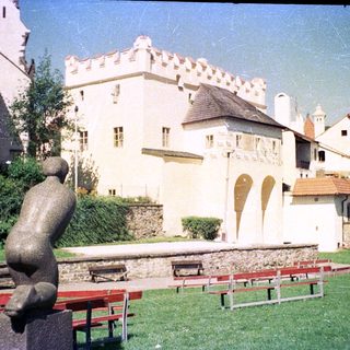 Medieval castle with courtyard, benches, and sculpture.