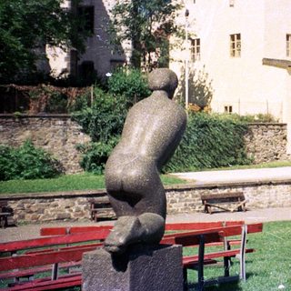 Medieval castle with courtyard, benches, and sculpture.