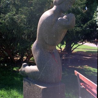 Abstract bronze sculpture of seated figure holding head.