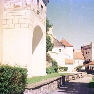 Medieval castle courtyard with stone buildings and greenery.