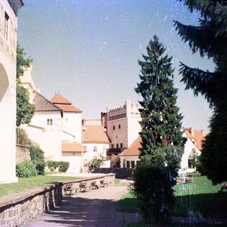 Medieval castle courtyard with stone buildings and greenery.