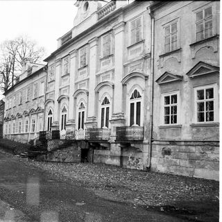 Neoclassical building with arched windows, gravel courtyard.