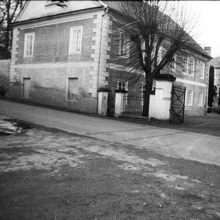 Two-story building with gated entrance, bare trees, and empty street.