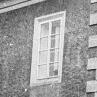 Two-story building with weathered facade on wet street.
