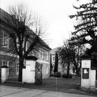 Historic street entrance with gated buildings and bare trees.