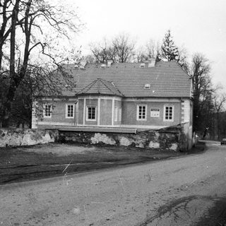 Vintage photo of a two-story house on elevated stone foundation.
