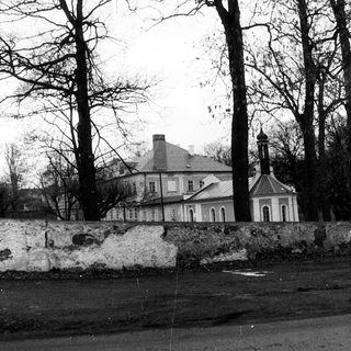 Historic building surrounded by bare trees and stone wall.